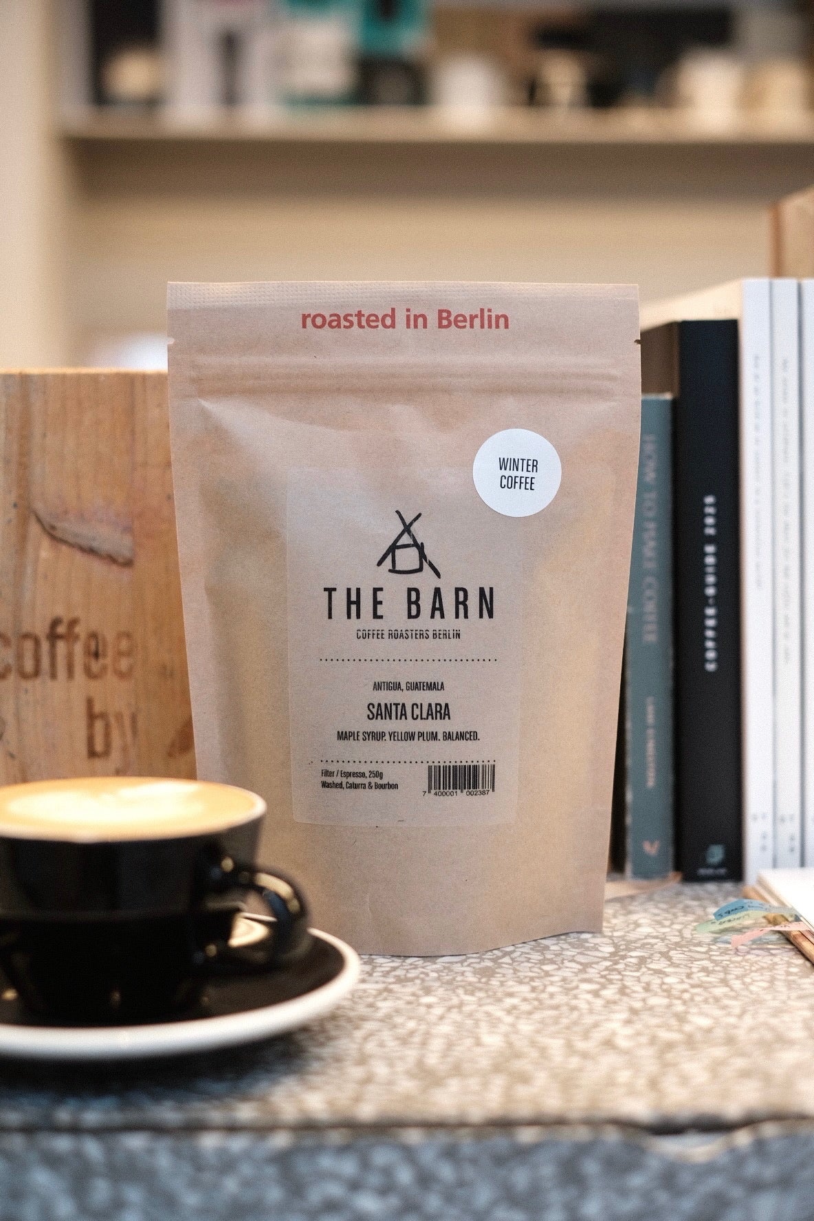 Winter Coffee: Santa Clara Coffee bag labeled 'The Barn' with a cup of coffee on a table.