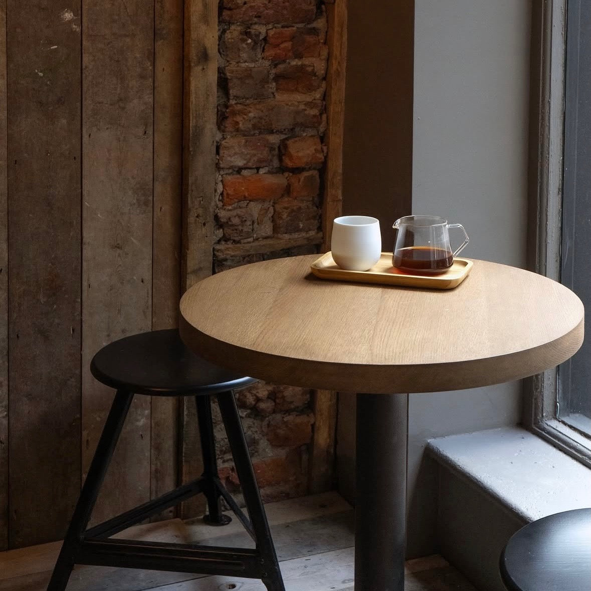 A V60 filter brew and white cup on wooden table at THE BARN London.